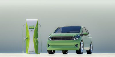 Modern electric car with electric charging station. Vehicle and charging station are not based on any real brands or model - custom modeled and designed.